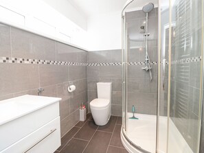 A modern bathroom with a shower, toilet, and sink.