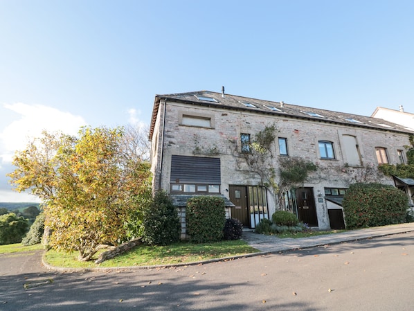 A two-story stone building with a traditional facade, a front entrance, and a small garden area.