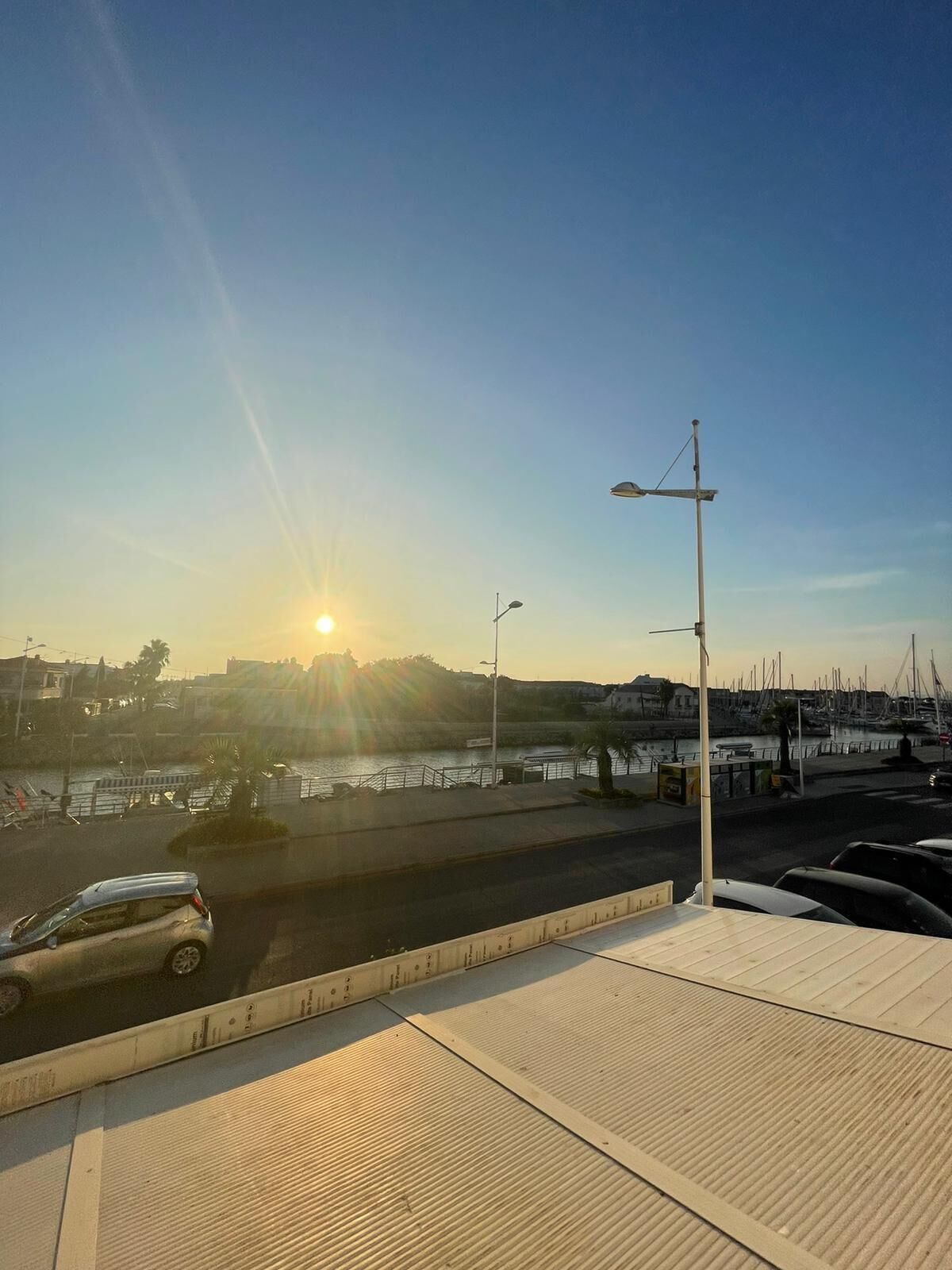 Een jachthaven met boten, een heldere lucht en een zonsondergang.