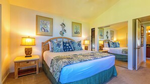 A bedroom with a large bed, two bedside tables, a mirror, and artwork on the walls. - Exquisite Prime Beachfront Haven, Indulge in Tropical Luxury -Wailea Elua 1302 (Wailea, Maui)