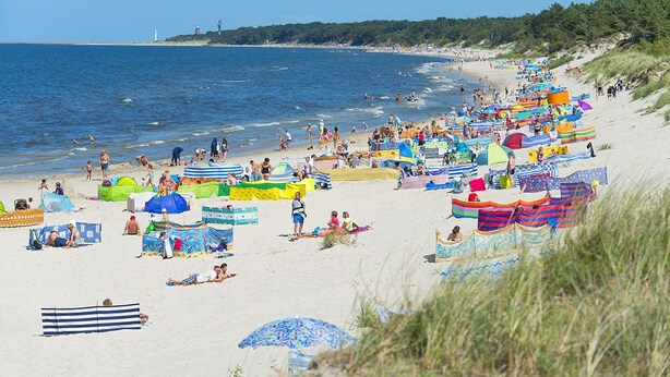 A beach with colorful umbrellas and beachgoers. - Seaside Apartamenty Kasprowicza 14  (Kolobrzeg)