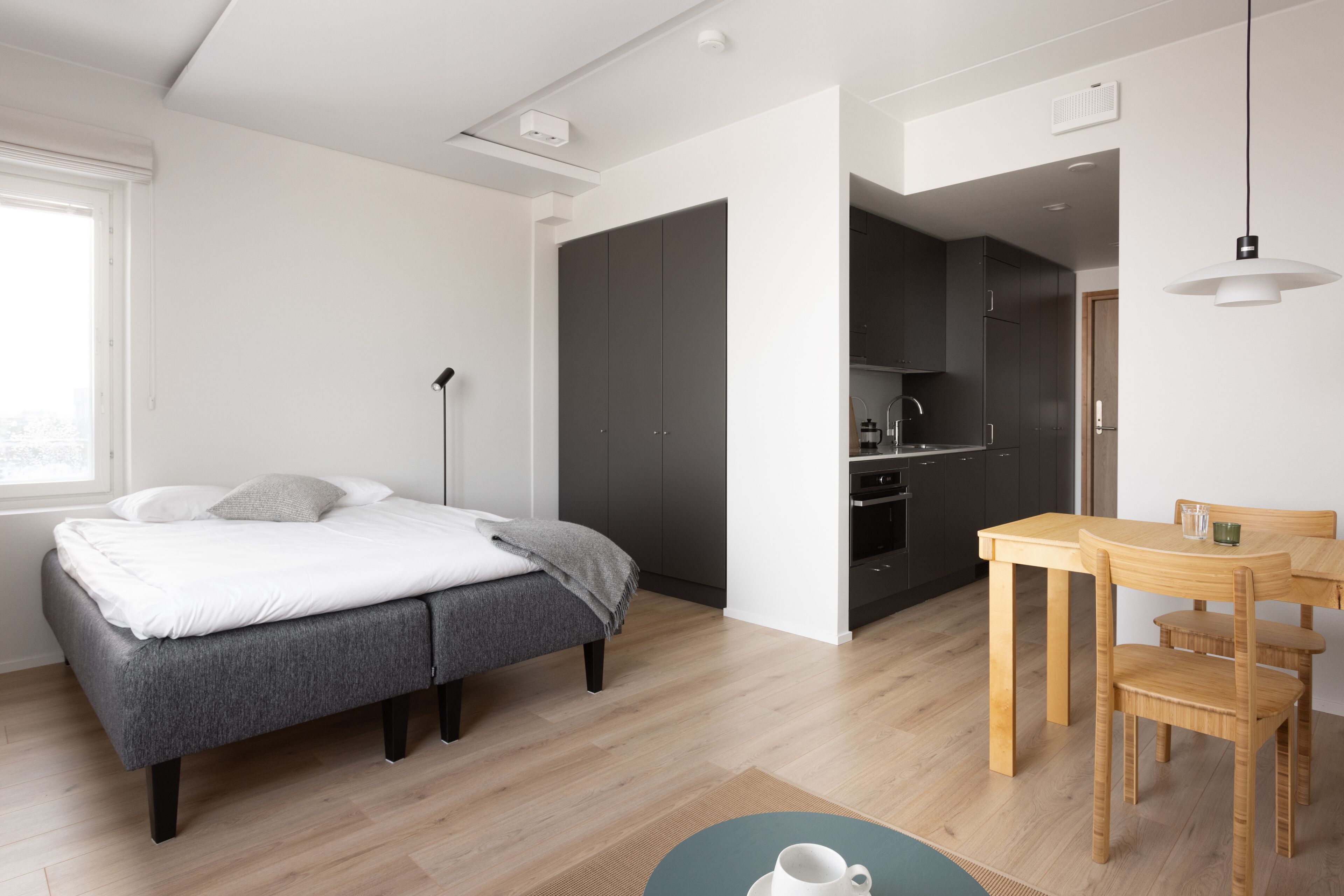 Un dormitorio moderno con cama, mesita de noche y vistas a la cocina.