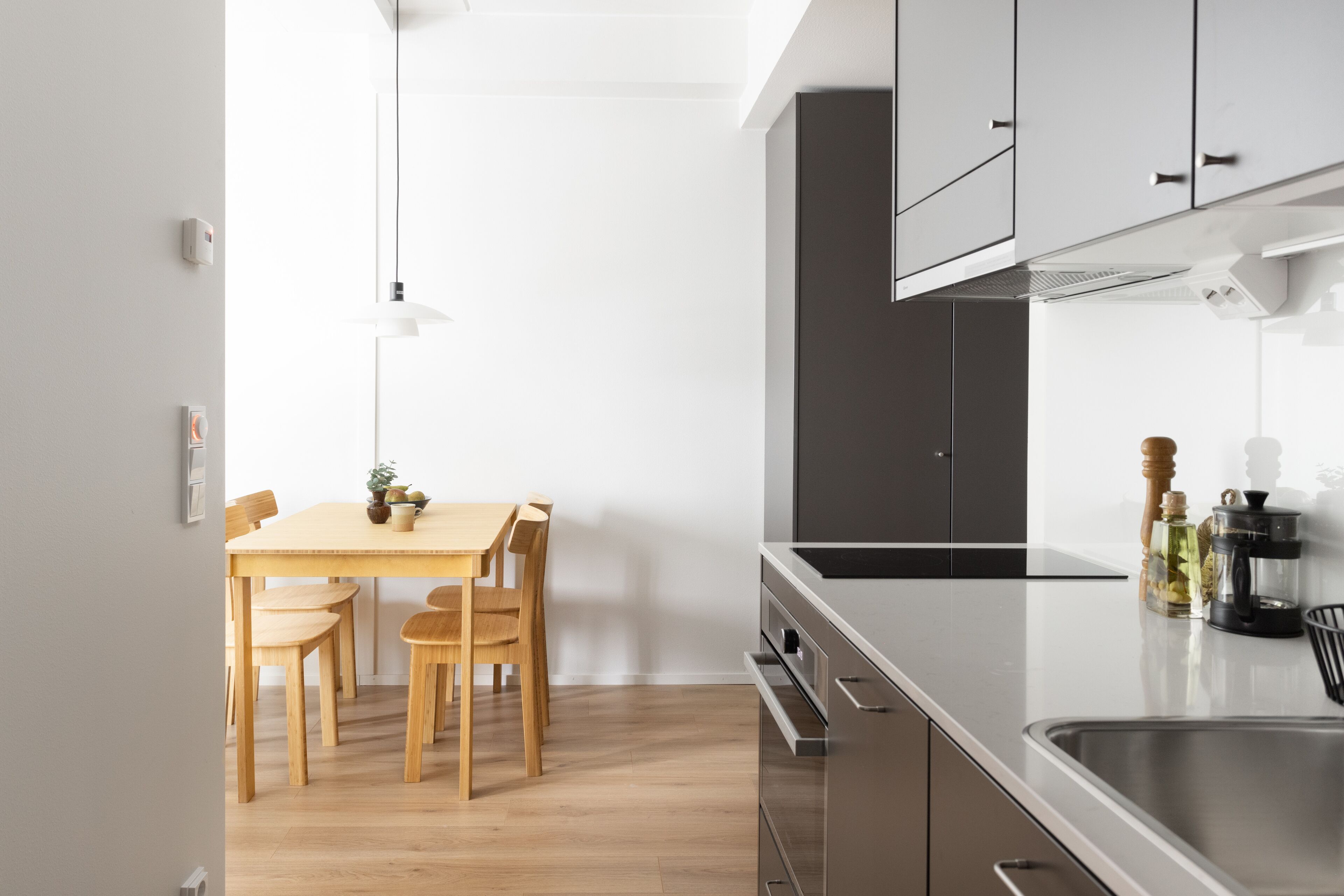 Una cocina moderna con una mesa y sillas de madera, electrodomésticos de acero inoxidable y un diseño limpio y minimalista.