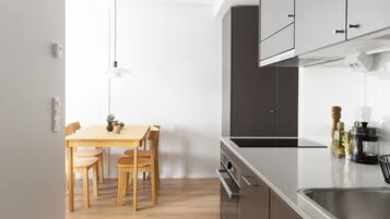 Una cocina moderna con una mesa y sillas de madera, electrodomésticos de acero inoxidable y un diseño limpio y minimalista.