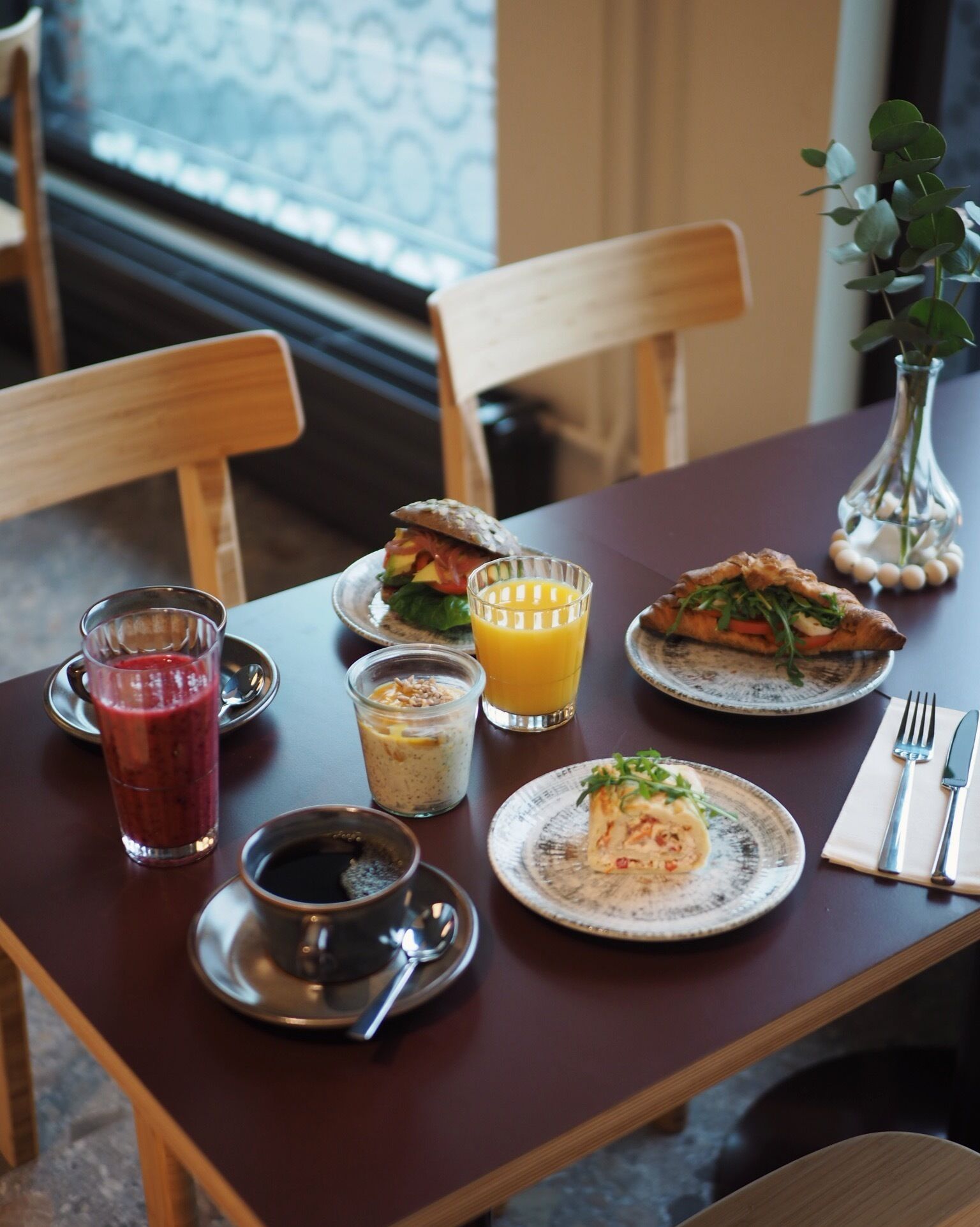 Ein Esstisch mit Frühstücksangeboten, darunter ein Smoothie, Saft und Gebäck.