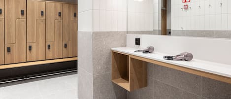 A modern bathroom with wooden lockers, a white sink, and a mirror.