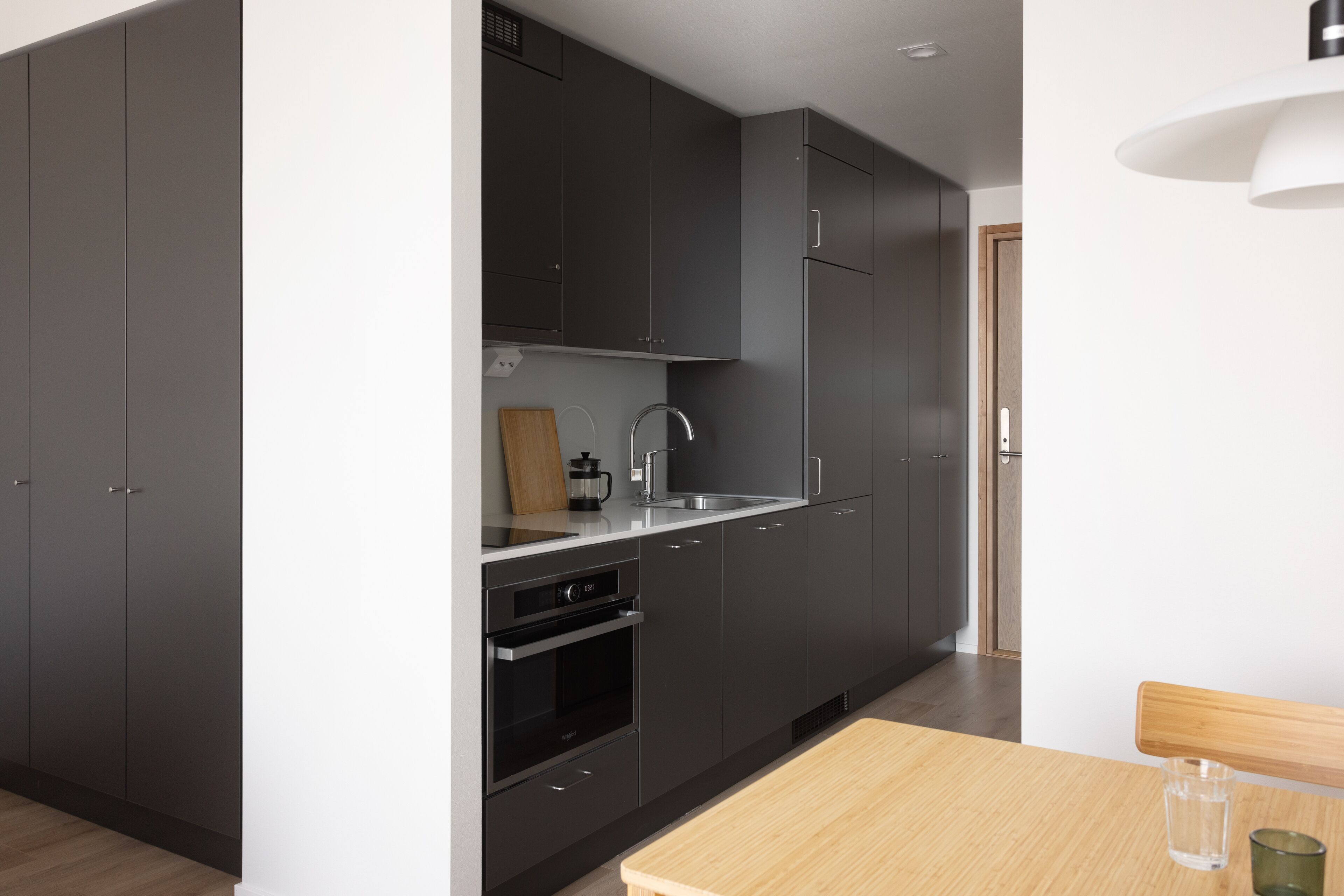 Una cocina moderna con armarios oscuros, un lavamanos de acero inoxidable y una mesa de madera.