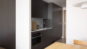 Una cocina moderna con armarios oscuros, un lavamanos de acero inoxidable y una mesa de madera.