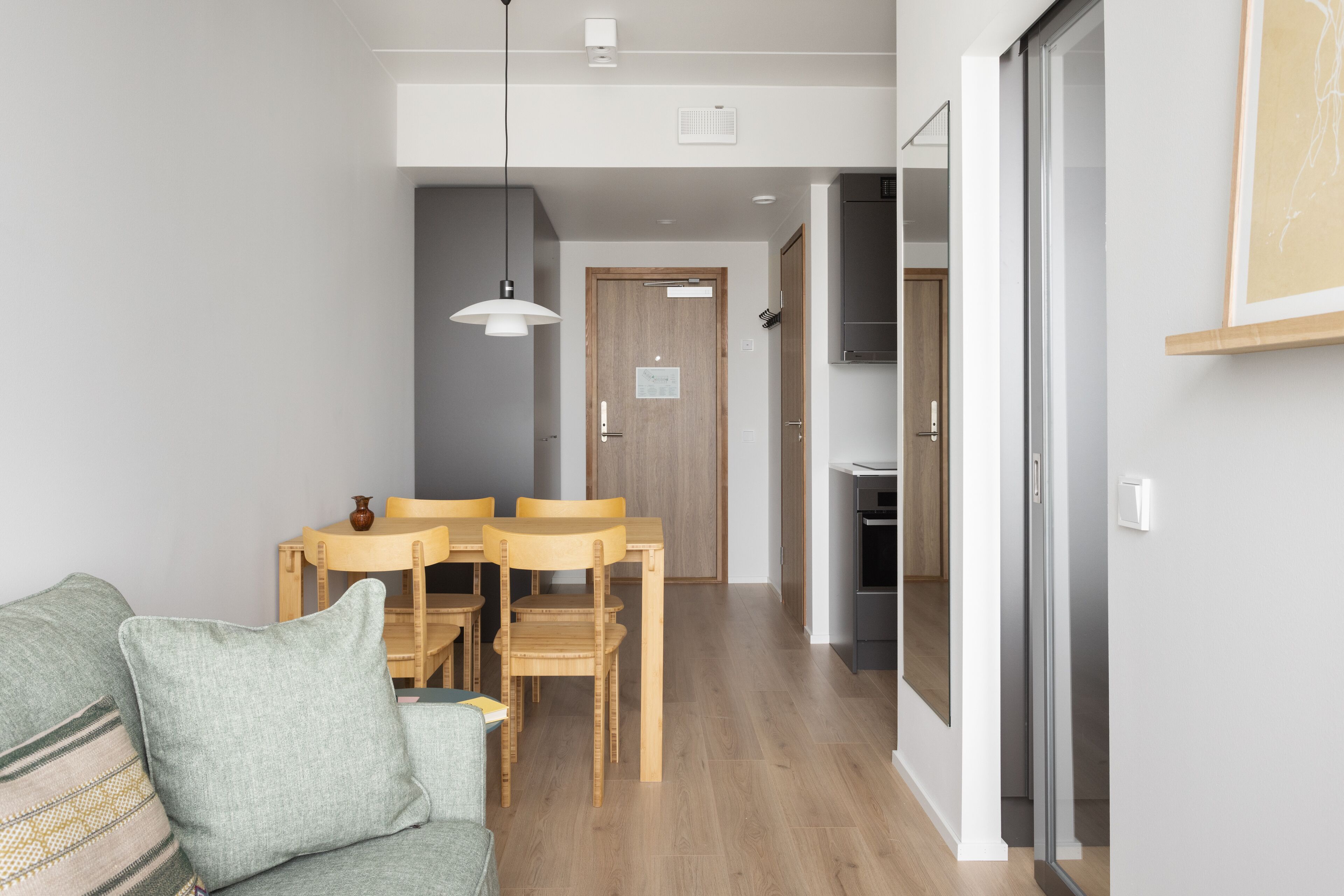 Una sala de estar moderna con un sofá, una mesa de comedor con sillas y una cocina al fondo.