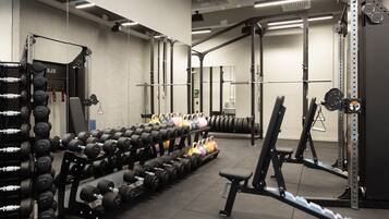 Ein Fitnessraum mit Gewichtstrainingsgeräten, darunter Kurzhanteln und ein Squat-Rack.
