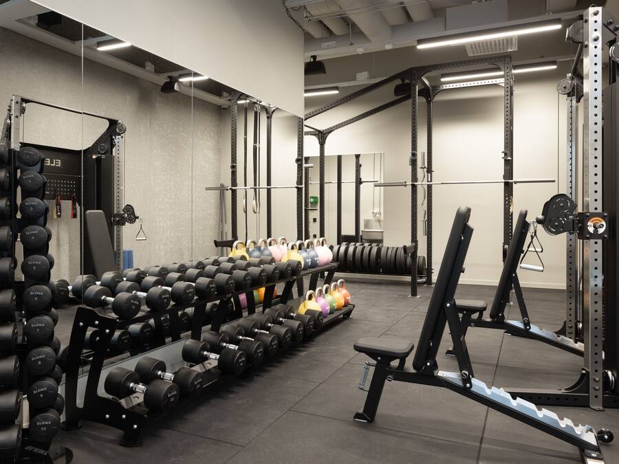 Ein Fitnessraum mit Gewichtstrainingsgeräten, darunter Kurzhanteln und ein Squat-Rack.