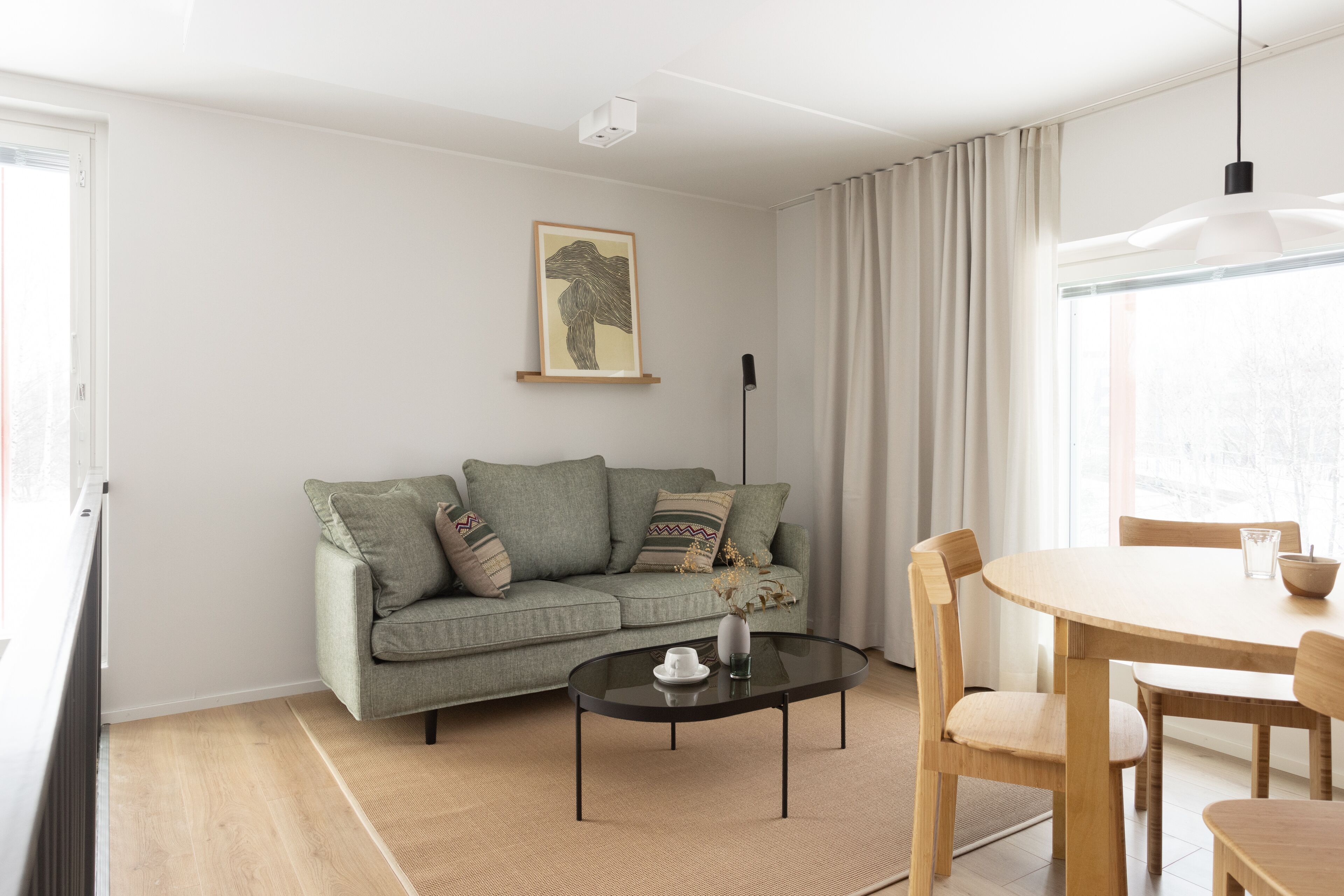 A modern living room with a sofa, a glass coffee table, and a dining table with chairs.