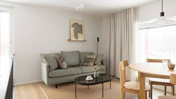 A modern living room with a sofa, a glass coffee table, and a dining table with chairs.