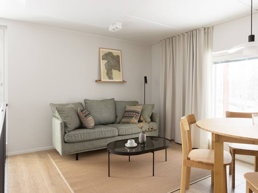 A modern living room with a sofa, a glass coffee table, and a dining table with chairs.