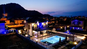 A modern house with a swimming pool, outdoor seating, and a well-lit patio area. - BEAUTIFUL 4 BEDROOM VILLA WITH PRIVATE POOL&GARDEN IN HEART OF DALYAN MARAS AREA (Dalyan)