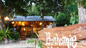 Puinen kyltti, jossa lukee ”Benhomi Beach Cottage”, ja taustalla näkyy perinteinen rakennus.