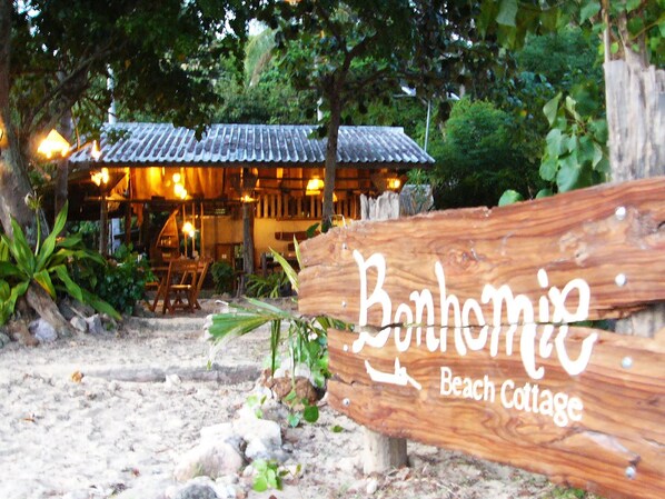 A wooden sign with the text 'Bonhomie Beach Cottage' indicating the name of the establishment.