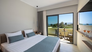A hotel room with a large bed, a balcony with a table and chairs, and a view of the landscape. - Mare Garden (Apokoronas)