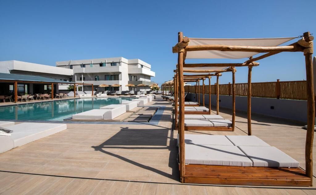A rooftop pool area with sun loungers and a wooden pergola.