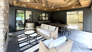 Un patio extérieur abrité, doté d’un mur en pierre, de meubles en osier et d’un espace barbecue.