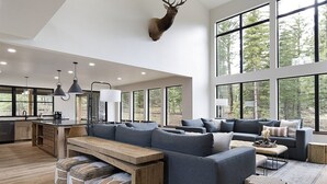 Un vaste espace de vie comprenant un grand canapé, une table basse en bois et une tête de cerf fixée au mur.