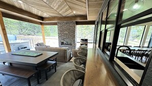 Un espace extérieur abrité, aménagé pour les repas, avec une cheminée en pierre, des chaises en osier et une longue table en bois.