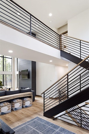 Un intérieur moderne comprenant un escalier, un coin salon et un téléviseur à écran plat.
