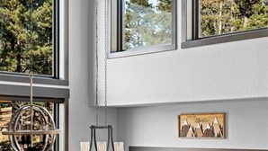 Un comedor moderno con una mesa grande, sillas y una parrilla afuera de la ventana.