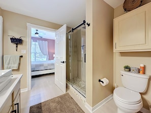 A bathroom with a toilet, a shower, a sink, and a mirror.