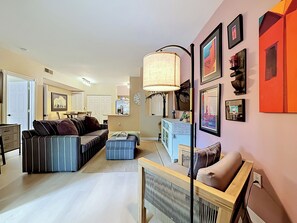 A living room with a sofa, ottoman, and a dining area with a table and chairs. - Clearwater Resort-Like Gulf Coast Beach Oasis (Clearwater)