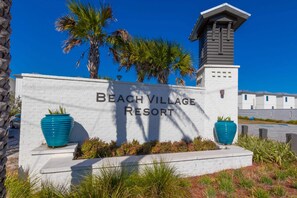 Welcome to Beach Village Resort, where guests can enjoy a tropical getaway amidst palm trees and a clear blue sky.