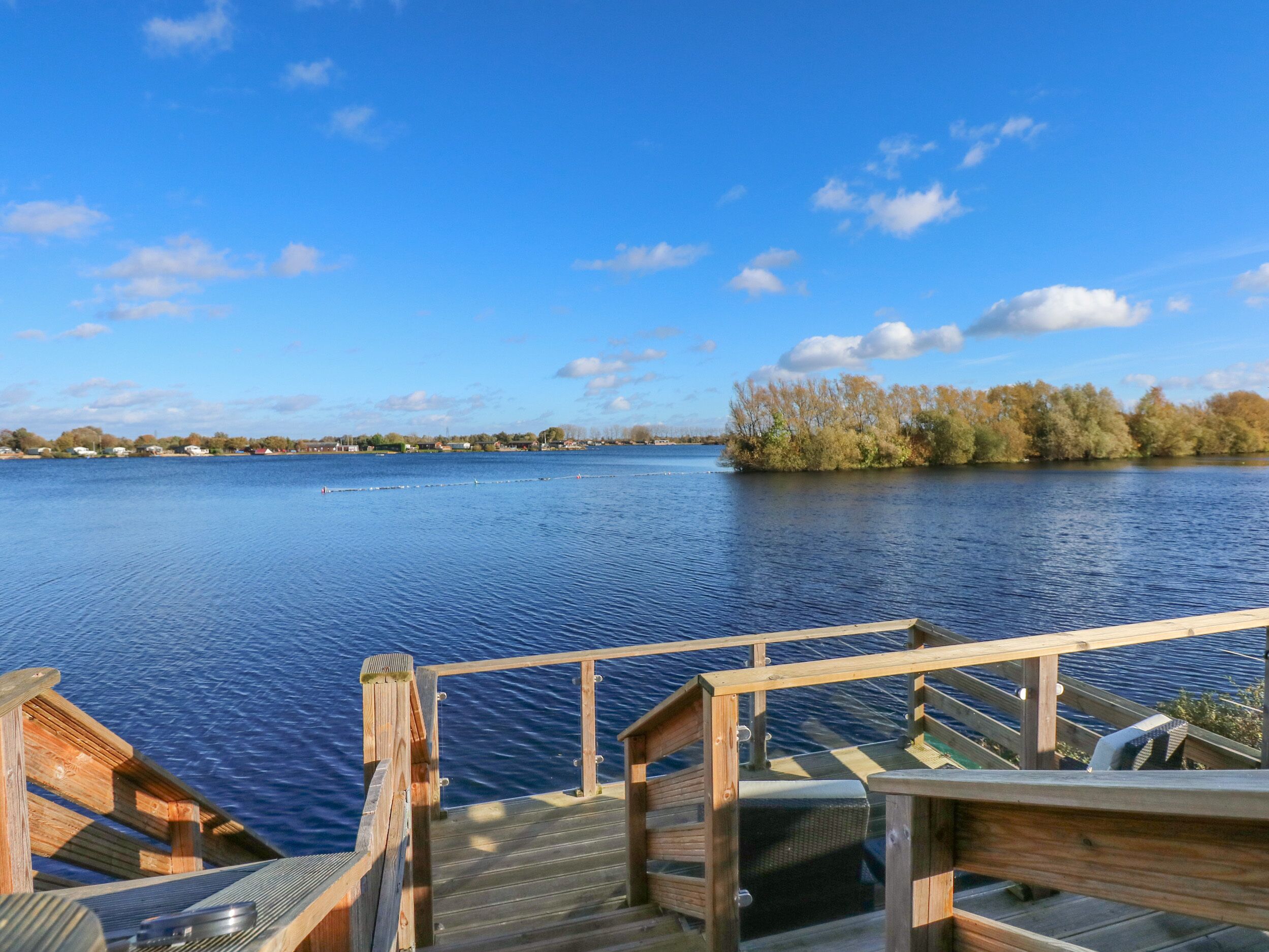 A wooden dock leading to a calm lake with a clear sky.