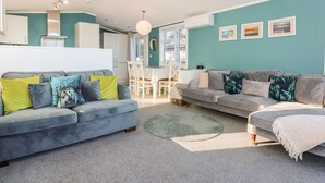 A modern living room with two sofas, a dining table, and a kitchen area. - Lake View Lodge (Bedford)