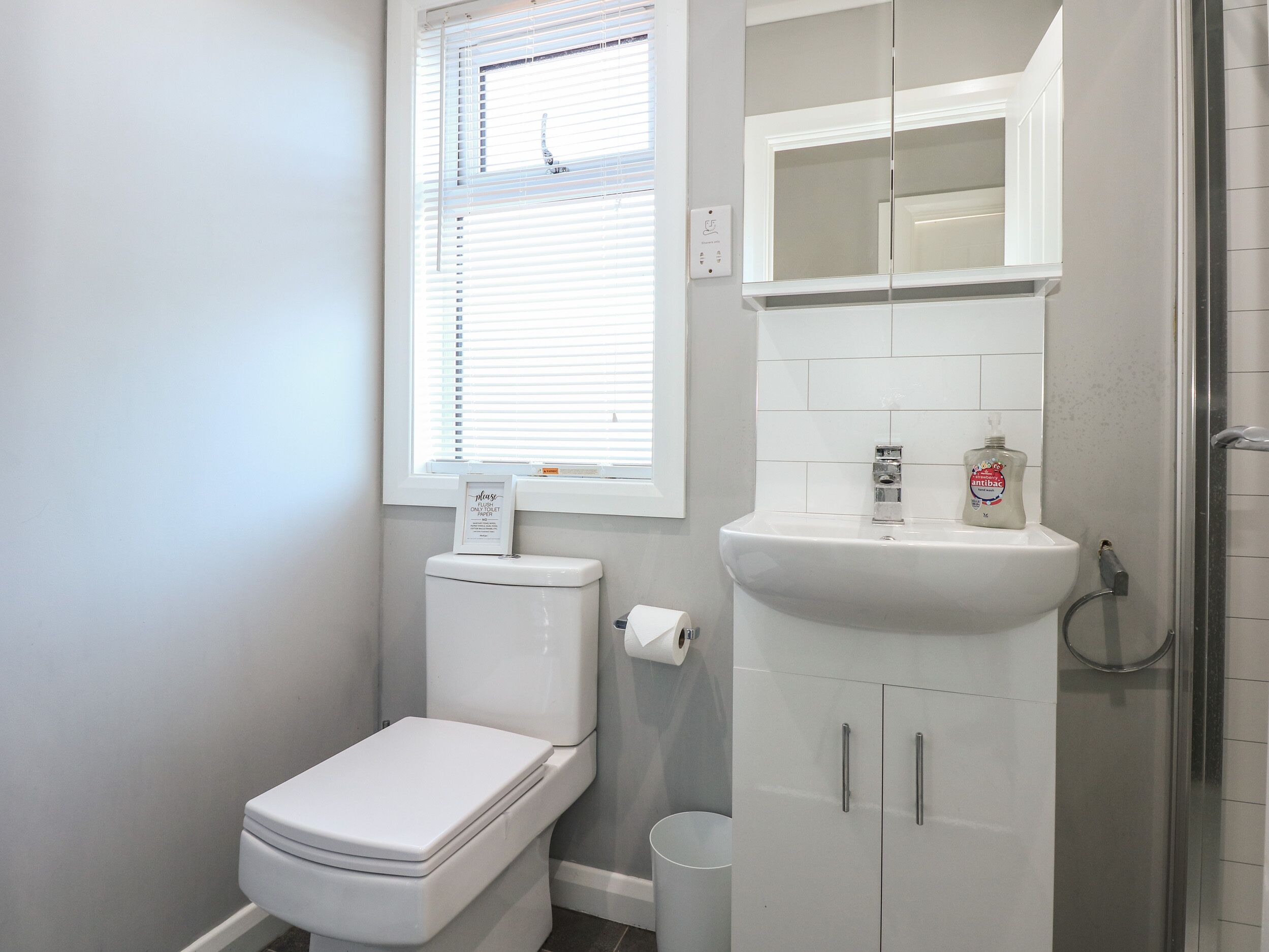 A bathroom with a toilet, sink, and shower.
