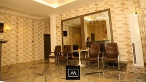 A conference room with a marble floor, a large mirror, and several brown chairs around a white table. - Mo-House Hotels and Apartments (Abuja)