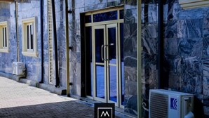 A building facade with a marble-like exterior, a glass door entrance, and an air conditioning unit outside. - Mo-House Hotels and Apartments (Abuja)