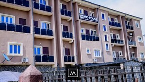 A multi-story hotel with balconies, air conditioning units, and a sign indicating it is a hotel and apartment complex. - Mo-House Hotels and Apartments (Abuja)