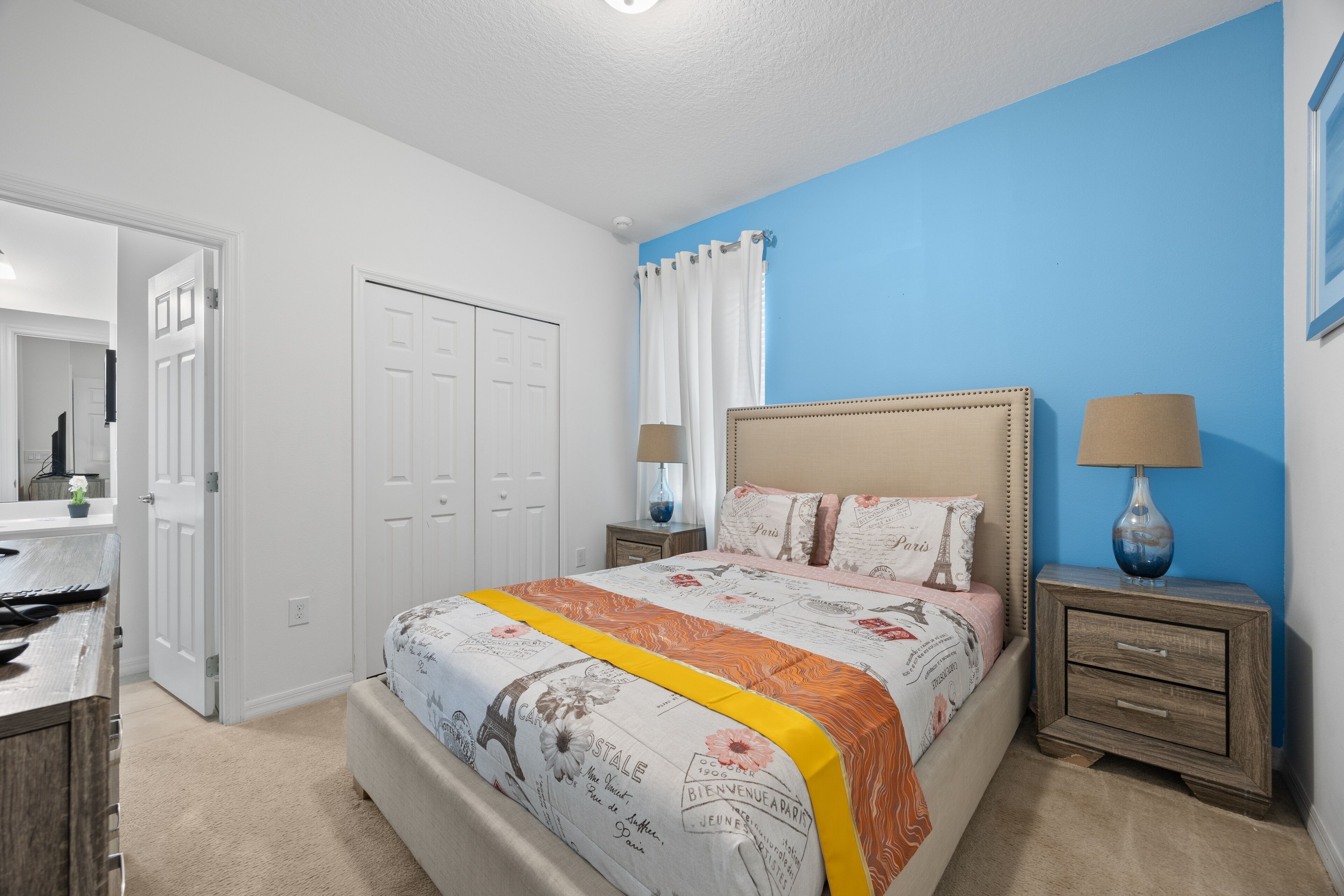 A bedroom with a bed, nightstands, a dresser, and a door.