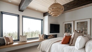 Een slaapkamer met een groot bed, een aan de muur bevestigde televisie en een open haard.