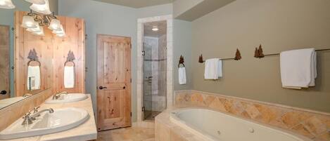 A bathroom with two sinks, a large bathtub, and a shower area.