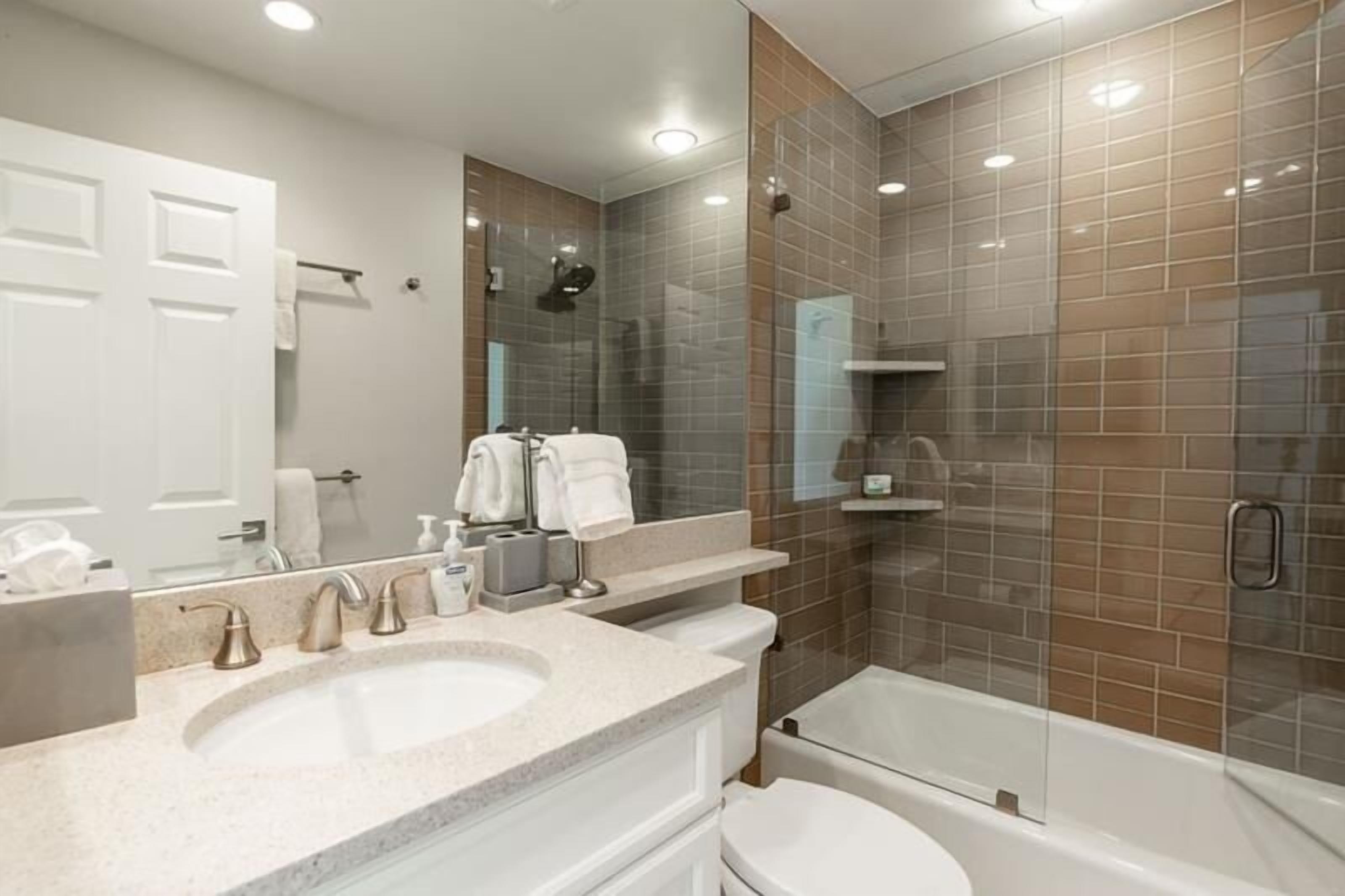 Un baño moderno con un lavamanos grande, un inodoro y una ducha con mampara de vidrio.