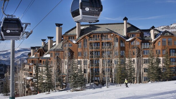Une station de ski dotée d’un télécabine, de bâtiments en bois et d’un paysage enneigé.