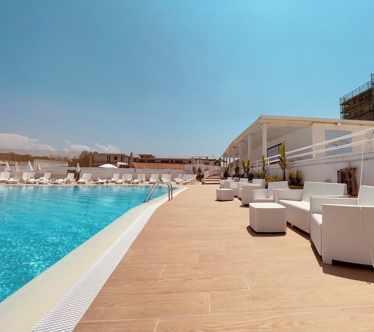 Un espace aménagé au bord de la piscine, avec des chaises longues et une piscine à l’eau d’un bleu limpide.