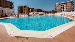 A swimming pool with lounge chairs and a clear blue sky. - Demetra Sea Front Apartment (Castel Volturno)