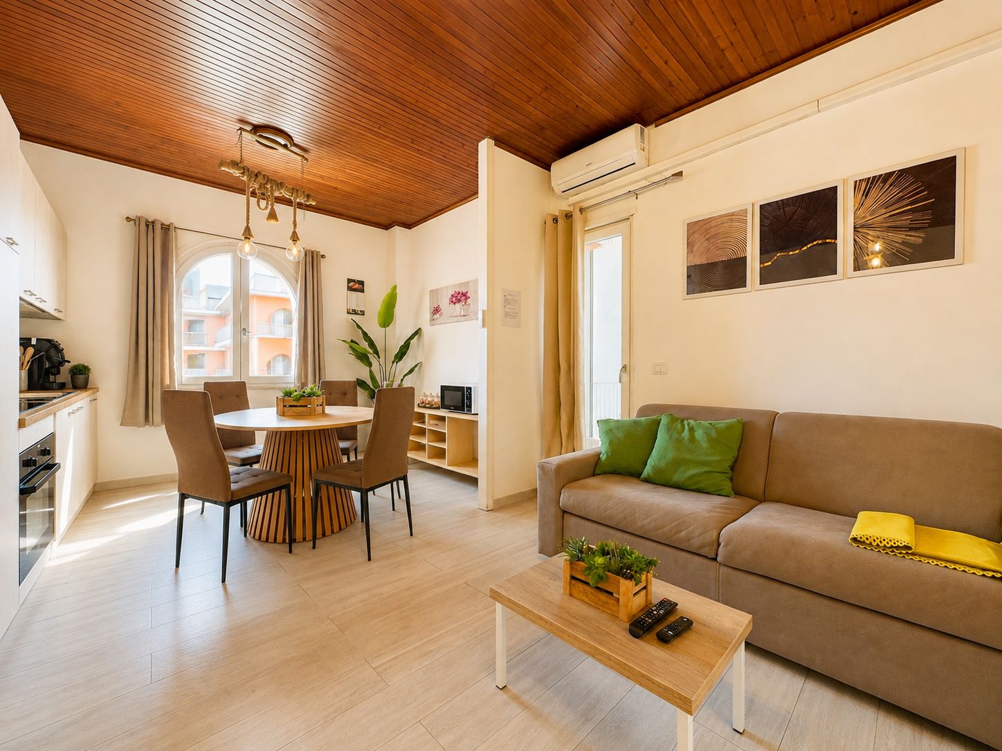 Un soggiorno moderno con soffitto in legno, un divano, un tavolino da caffè e un'area pranzo con sedie e tavolo.