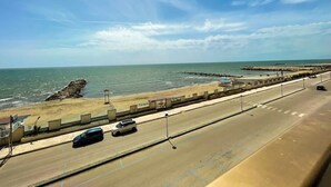 Une route côtière, avec une plage d’un côté et un ciel dégagé de l’autre.