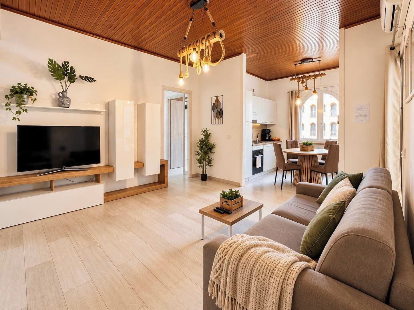 Ein modernes Wohnzimmer mit Fernseher, Holzboden und einer gemütlichen Couch.