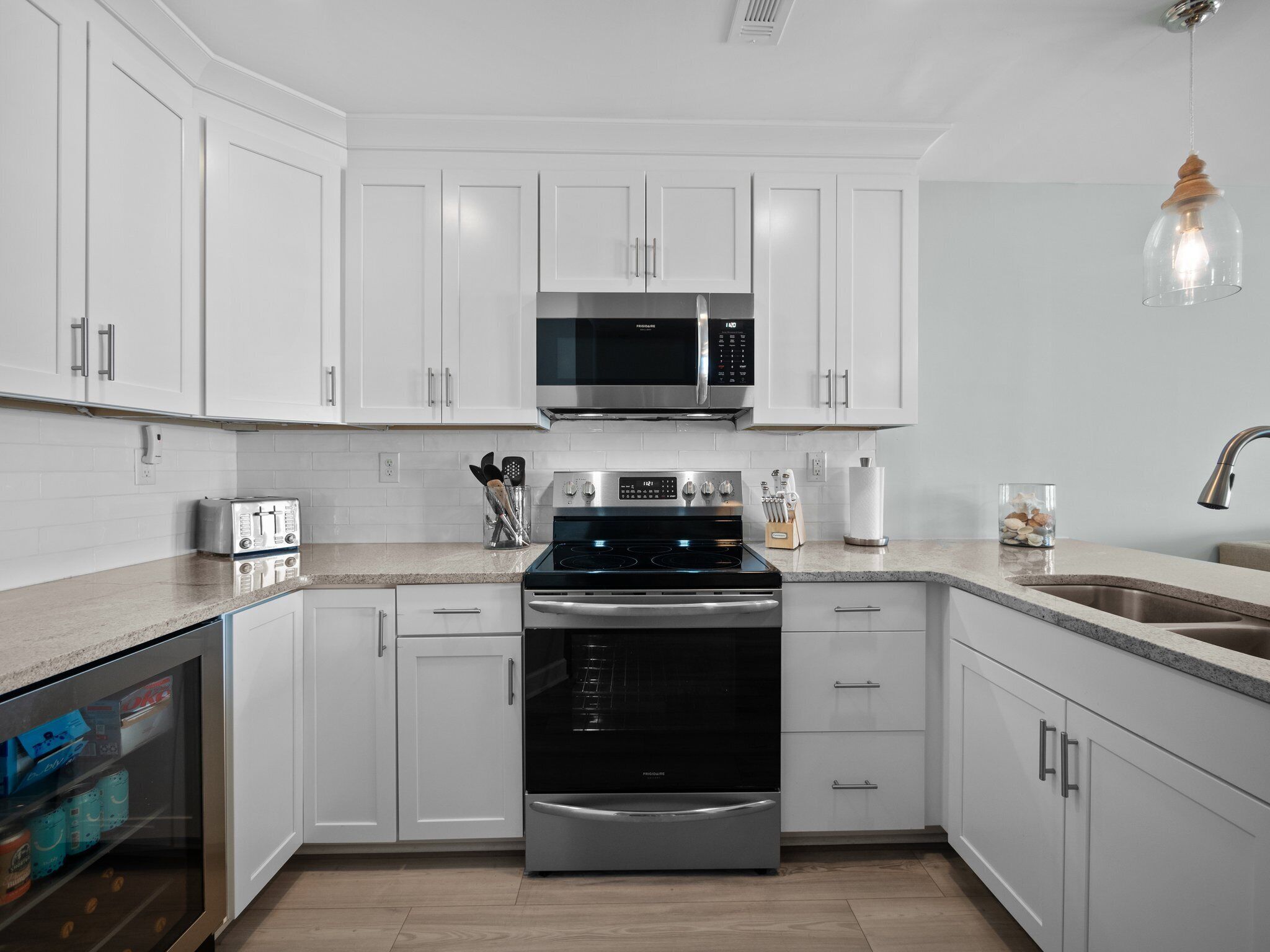 Una cocina moderna con armarios blancos, electrodomésticos de acero inoxidable y encimera de granito.