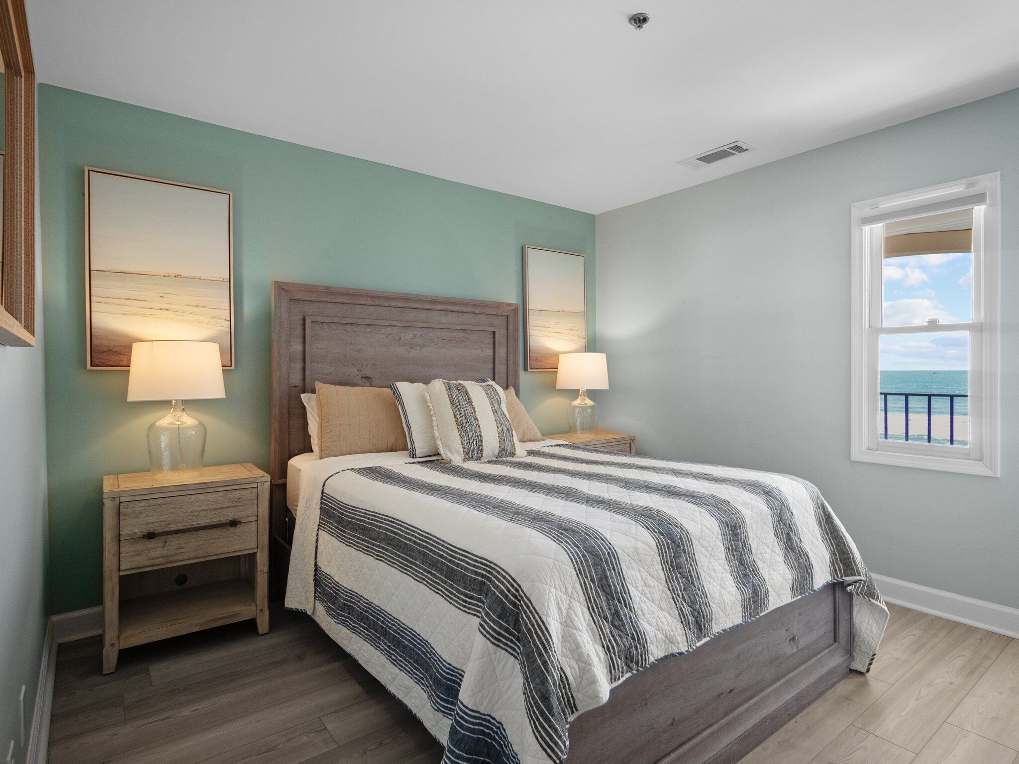 A bedroom with a bed, two bedside tables, two lamps, and two framed pictures on the wall.