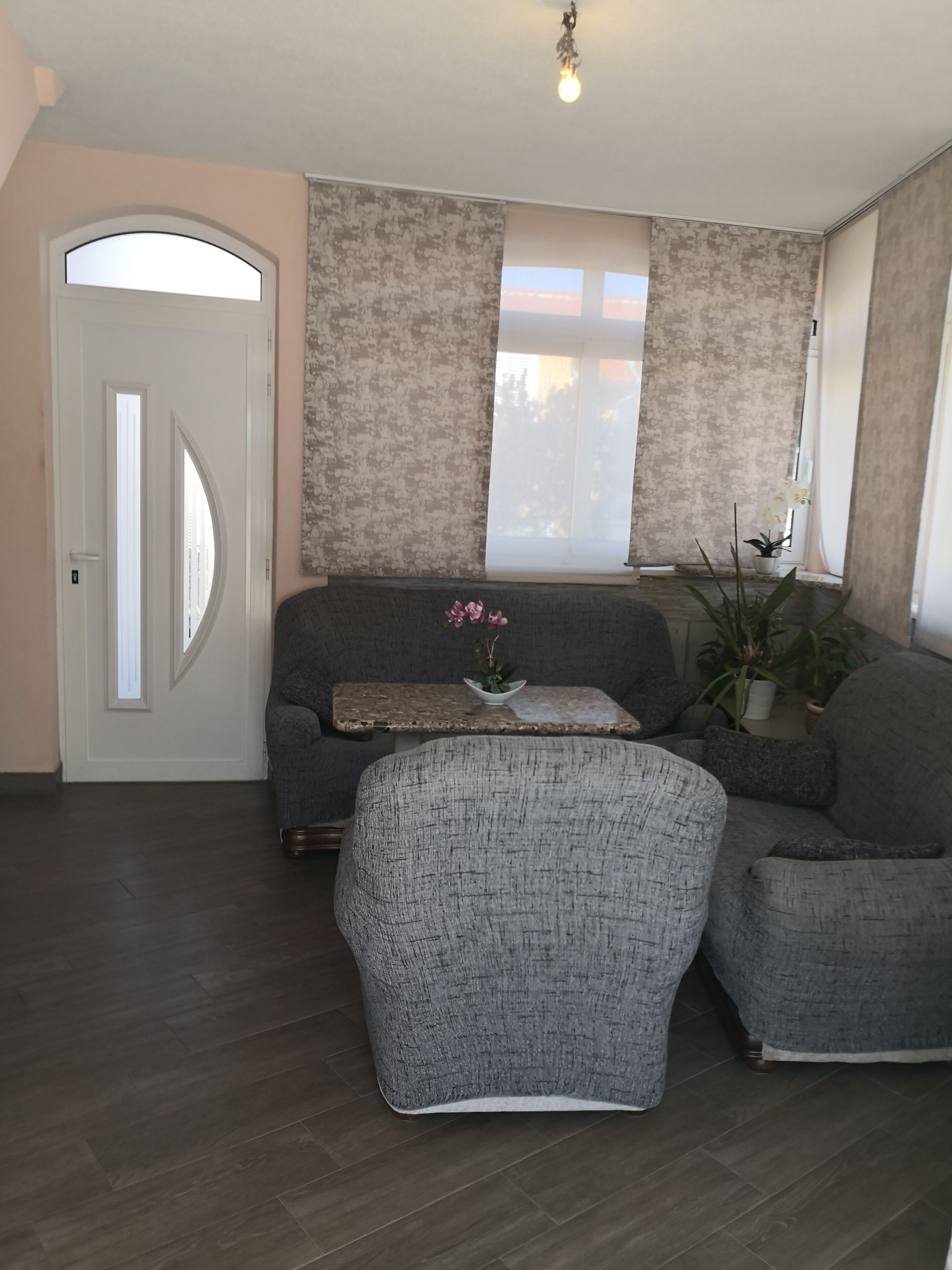 Una sala de estar con un sofá gris, un sillón a juego, una mesita con una planta y una ventana con vistas.